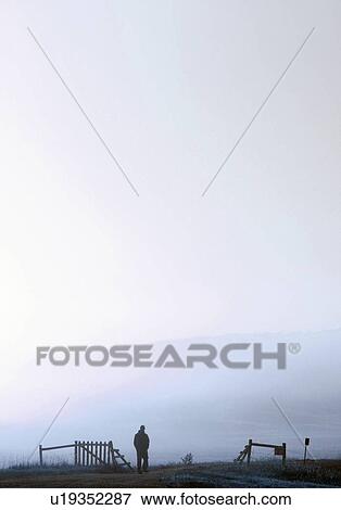 Stock Photo - Misty morning, person walking toward gate. Fotosearch