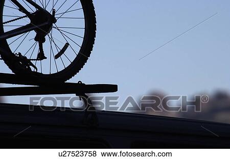 Stock Photo - Mountain bike silhouette on the roof of a car in Arches National Park Utah,. Fotosearch