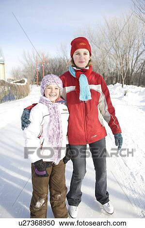 Stock Image - Portrait of 9 and 13-year old girls in skates, The Forks, Winnipeg, Canada. Fotosearch