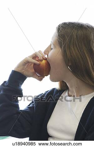 Stock Photography - Pre-teen girl eating organic apple, wearing hoodie made with hemp fibre, Canada, Manitoba, Brandon. Fotosearch