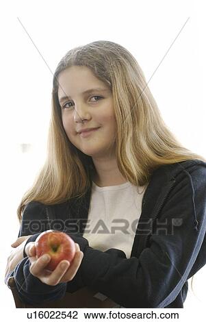 Stock Image - Pre-teen girl holding organic apple, wearing hoodie made with hemp fibre, Canada, Manitoba, Brandon. Fotosearch