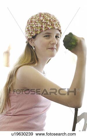 Stock Photo - Pre-teen girl holding organic broccoli like a hand weight, wearing shirt made with hemp fibre, Canada, Manitoba, Brandon. Fotosearch