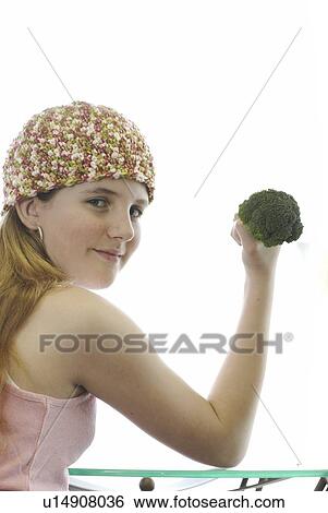 Stock Photograph - Pre-teen girl holding organic broccoli like a hand weight, wearing shirt made with hemp fibre, Canada, Manitoba, Brandon. Fotosearch