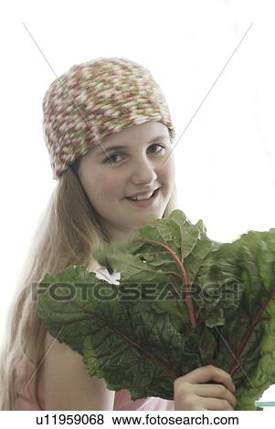 Stock Photo - Pre-teen girl holding organic red chard, wearing shirt made with hemp fibre, Canada, Manitoba, Brandon. Fotosearch