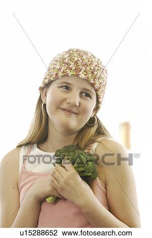 Stock Image - Pre-teen girl holding organic broccolli, wearing shirt made with hemp fibre, Canada, Manitoba, Brandon. Fotosearch