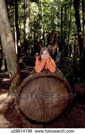 Stock Photo - Pre-teen girl with face in hands on Douglas Fir, Vancouver Island, Canada. Fotosearch