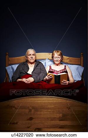 Senior couple in bed, female reading, man appears dispondent View Large Photo Image Stock Image - Senior couple in bed, female reading, man appears dispondent. Fotosearch