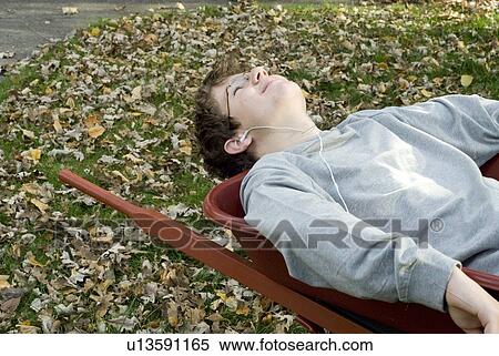 Stock Photography - Teen boy listening to music in wheelbarrow, Winnipeg, Canada. Fotosearch