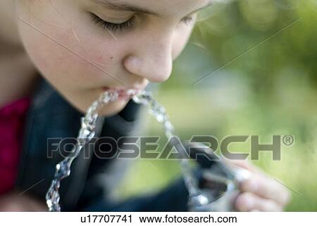 Stock Image - Twelve year old girl drinks from water fountain in park, Winnipeg, Canada. Fotosearch