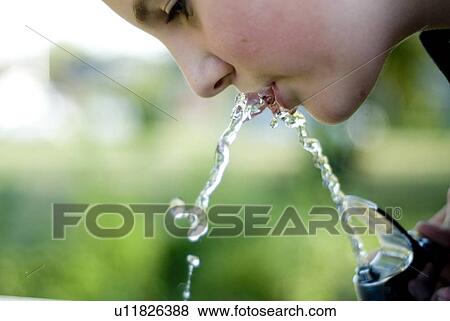 Stock Photo - Twelve year old girl drinks from water fountain in park, Winnipeg, Canada. Fotosearch