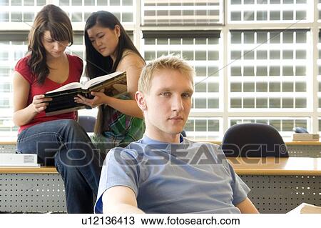 Stock Image - Two female students in background, male in foreground, in front of solar panelled windows, Winnipeg, Canada. Fotosearch