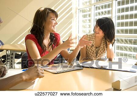 Stock Photo - Two female students seated, talking, Winnipeg, Canada. Fotosearch