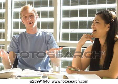 Stock Photograph - Two students seated, talking, in front of solar panelled windows, Winnipeg, Canada. Fotosearch