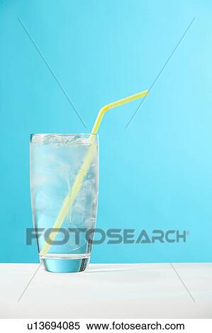 Stock Photography - Very full glass of water with ice and yellow drinking straw. Fotosearch