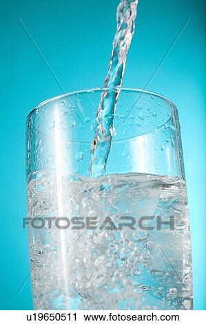 Stock Image - Water pouring into nearly full glass. Fotosearch