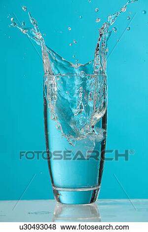Water splash as ice cube drops into glass of water View Large Photo Image Stock Photo - Water splash as ice cube drops into glass of water. Fotosearch