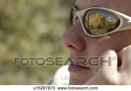 Stock Image - Woman (20-25) looking at rock cliffs with reflection of the cliffs in her sunglass lens, Smith Rock State Park, Oregon. Fotosearch