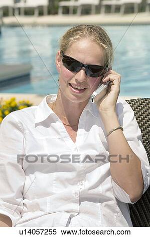 Stock Photography - Woman (35) talking on the cell poolside. Fotosearch