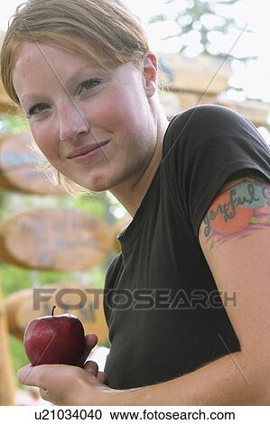 Stock Image - Woman holding apple, Wasagaming, Riding Mountain National Park, Manitoba, Canada. Fotosearch