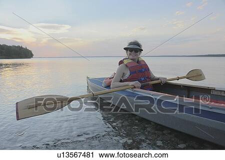 Stock Image - Woman in kayak Clear Lake Riding Mt. Nat. Park; Canada, Manitoba, Riding Mountain National Park. Fotosearch