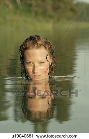 Stock Image - Woman in lake with face reflected in water, Lake Katherine, Riding Mountain National Park, Manitoba, Canada. Fotosearch