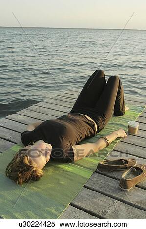 Woman lying on dock by lake, Clear Lake, Riding Mountain National Park, Manitoba, Canada View Large Photo Image Stock Photography - Woman lying on dock by lake, Clear Lake, Riding Mountain National Park, Manitoba, Canada. Fotosearch