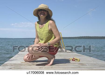 Stock Photo - Woman on dock; Canada, Manitoba, Riding Mountain National Park. Fotosearch