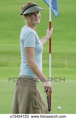 Stock Image - Woman on putting green, wearing hemp shirt, organic golf course, Clear Lake Golf Course, Riding Mountain National Park, Manitoba, Canada. Fotosearch