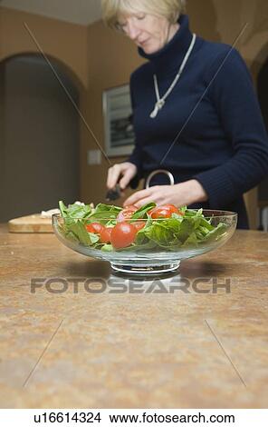 Picture - Woman preparing tomato salad. Fotosearch