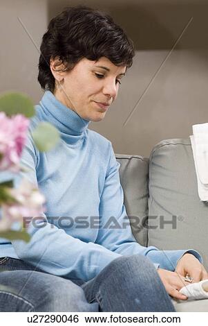 Stock Photograph - Woman seated on sofa folding cloth diapers, Winnipeg, Canada. Fotosearch