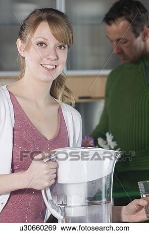 Stock Photo - Woman with glass of water from filtred jug. Fotosearch