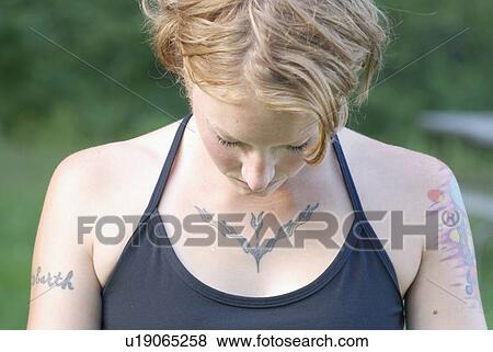 Stock Photo - Woman with tattoos with head lowered, Grayling Lake, Riding Mountain National Park, Manitoba, Canada. Fotosearch