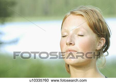 Stock Image - Woman's face with eyes closed, Grayling Lake, Riding Mountain National Park, Manitoba, Canada. Fotosearch