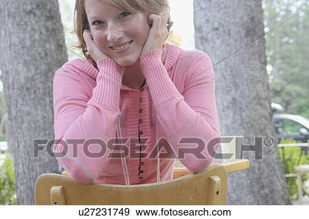 Stock Photo - Young woman sits backward on chair at outdoor restaurant, Wasagaming, Riding Mountain National Park, Manitoba, Canada. Fotosearch