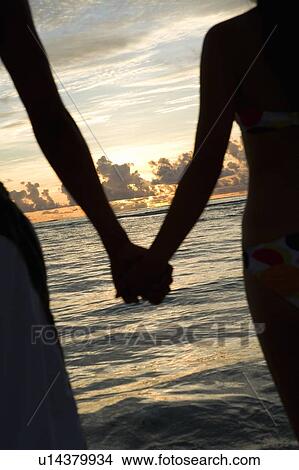 Picture - Young couple on beach, hand in hand, Saipan, USA . Fotosearch