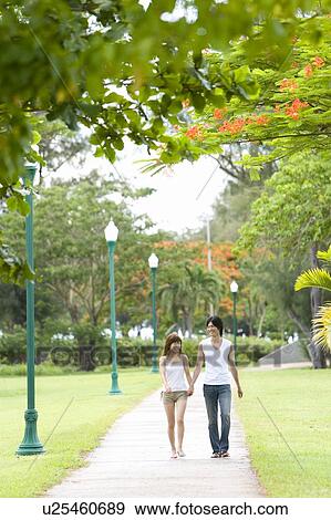 Stock Photo - Young couple smiling and walking hand in hand, Saipan, USA . Fotosearch