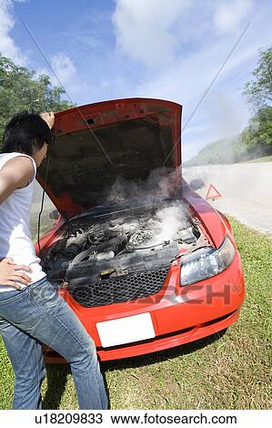 Stock Image - Young man looking at car engine, Saipan, USA . Fotosearch