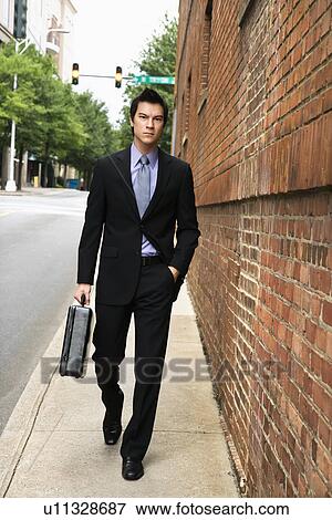 Asian business man walking down sidewalk in the city. View Large Photo Image Stock Photo - Asian business man walking down sidewalk in the city.. Fotosearch