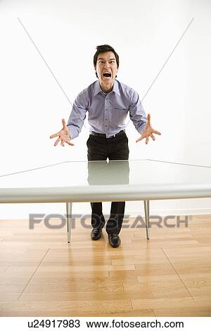 Business man standing at conference table yelling at unseen person View Large Photo Image Stock Image - Business man standing at conference table yelling at unseen person. Fotosearch