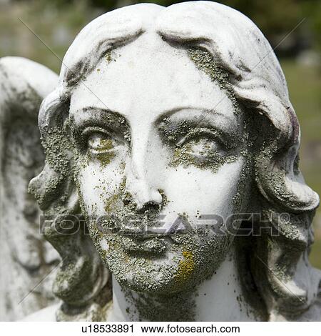 Stock Image - Close-up of Guardian Angel statue's face in graveyard.. Fotosearch