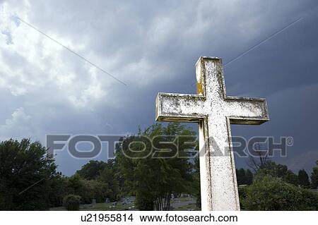 Picture - Cross in graveyard against stormy dark clouds in sky.. Fotosearch