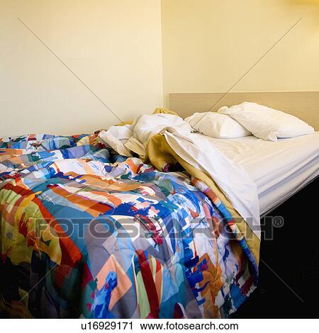 Stock Image - Interior shot of motel room with messy unmade bed. Fotosearch