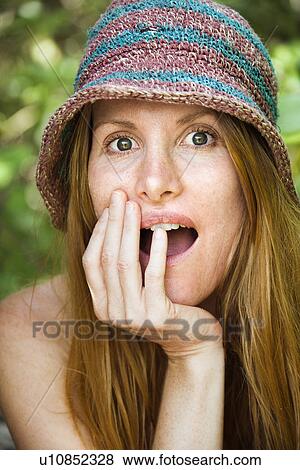 Stock Photo - Portrait of pretty redhead with surprised expression on her face wearing hat. Fotosearch