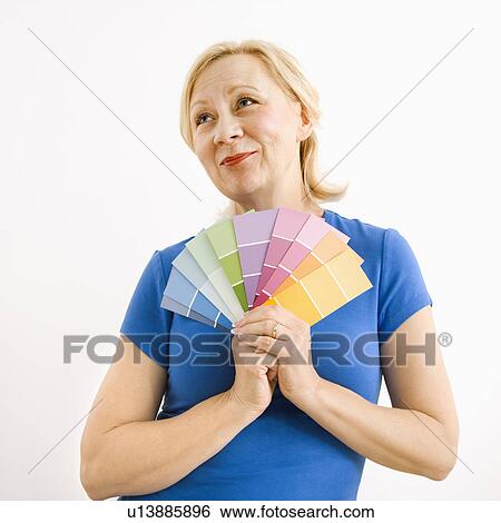 Stock Photograph - Portrait of smiling adult blonde woman holding paint swatches with hopeful expression.. Fotosearch