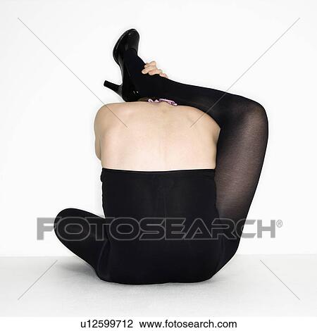 Portrait of young woman attempting to place her leg over her shoulders in a stretch View Large Photo Image Stock Image - Portrait of young woman attempting to place her leg over her shoulders in a stretch. Fotosearch