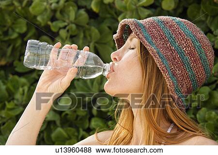 Side view of young redheaded woman wearing hat and drinking from water bottle. View Large Photo Image Stock Photo - Side view of young redheaded woman wearing hat and drinking from water bottle.. Fotosearch