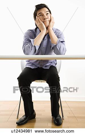 Young Asian business man sitting at desk daydreaming. View Large Photo Image Stock Image - Young Asian business man sitting at desk daydreaming.. Fotosearch
