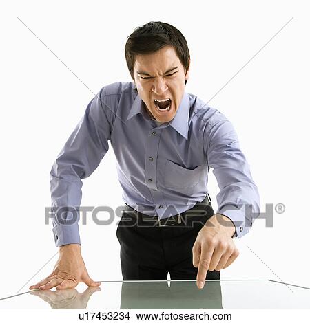 Picture - Young Asian business man standing yelling at unseen person.. Fotosearch