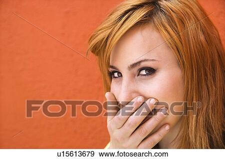 Stock Photo - Young redheaded woman laughing with hand over mouth.. Fotosearch