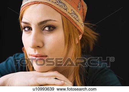 Stock Photo - Young redheaded woman wearing cap looking at viewer with serious expression. Fotosearch